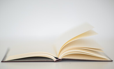 Closeup of a beautiful hardcover notebook with turning empty pages laying flat on a table. Isolated against a white background.