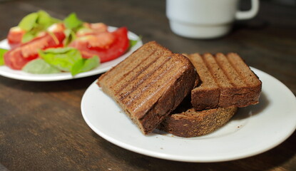  Fresh bread toast. Sliced tomatoes with lettuce on a white plate. Healthy eating concept
