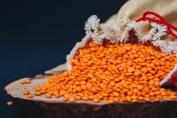 Red lentil seed grains spilling out of a bag close-up with copy space