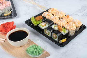 Sushi roll set with yellow cream sauce and shrimp in take away boxes