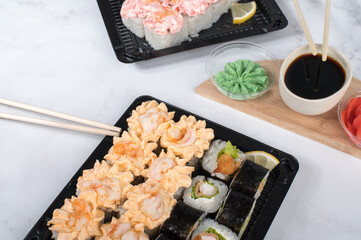 Sushi roll set with yellow cream sauce and shrimp in take away boxes