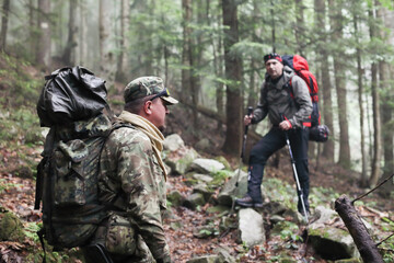 Two men hike in forest with backpack for trekking