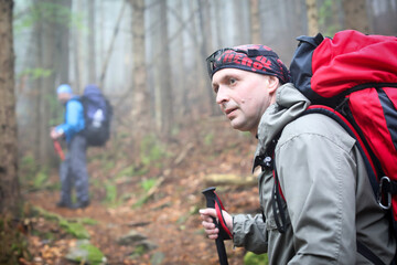 Naklejka premium Two men hike in forest with backpack for trekking