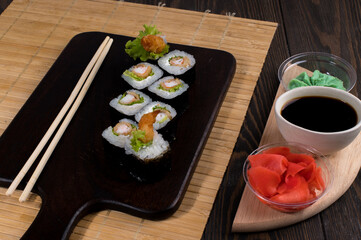 Sushi roll set with salad and fried shrimp on dark background