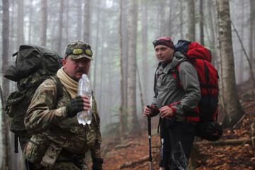 Fototapeta premium Two men hike in forest with backpack for trekking