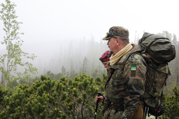 Active healthy man in camouflage hiking in beautiful forest