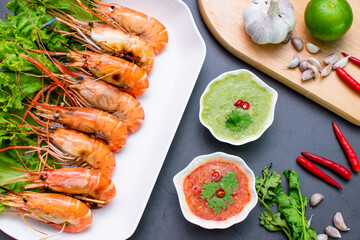 Top corner of freshly baked shrimp served on a plate with sauces, onions, garlic and chilies
