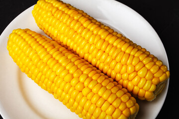 boiled corn on a white plate, close-up, selective focus