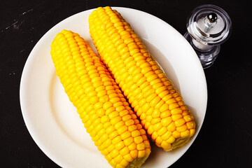 boiled corn on a white plate, top view