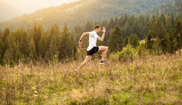 Running fitness man sprinting outdoors with beautiful mountains landscape on background. Runner training for marathon.