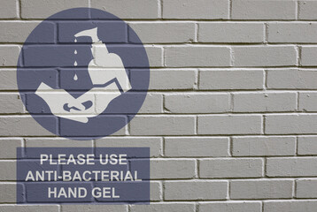 White decayed faded brick wall background with please use anti bacterial hand gel sign to stop the spread of the worldwide pandemic