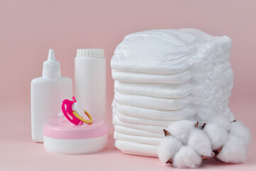 Fototapeta na wymiar Baby cosmetics, diapers and a nipple on pink.