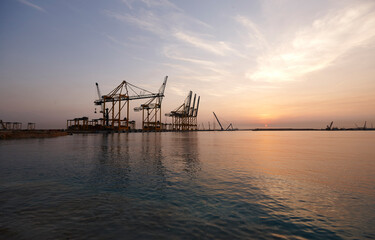 Naklejka na ściany i meble Cranes in seaport at sunrise.