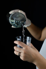 mano sirviendo agua en vaso de cristal