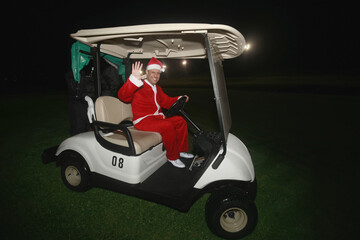 Man in Santa suit driving a golf cart