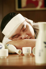 Man asleep on the table after a few cups of sake
