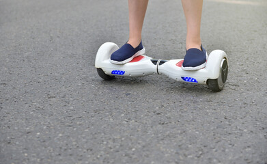 Electric hoverboard and legs of a girl child on a asphalt background