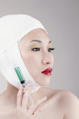 Woman with bandaged face holding a syringe
