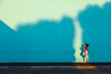 Young  woman bouncing. Shadow from sunset on the wall.