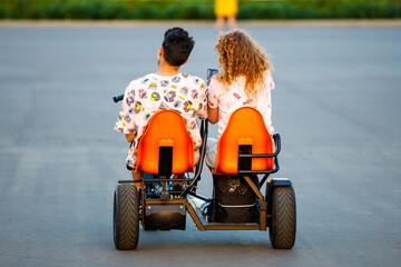 A young couple rides a tricycle