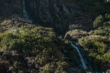 Fototapeta na wymiar Waterfall flowing between two tea houses, Annapurna circuit, Nepal