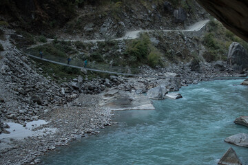 Three backpackers walking across a suspension bridge, Annapurna circuit, Nepal