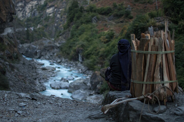 Strong working nepalese woman resting, sitting, looking at Marshyangdi river, Annapurna circuit, Nepal