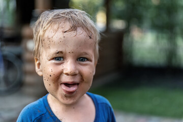 Cute adorable blond caucasian little happy toddler boy portrait with messy mus spots on face after...