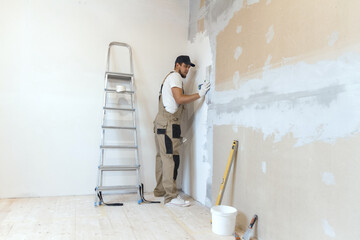 Male painter with a putty knife in his hands makes repairs