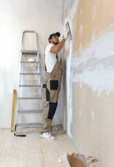 Male painter with a putty knife in his hands makes repairs