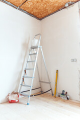 A stepladder with painting tools in a room. Preparing for putty