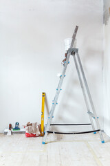 A stepladder with painting tools in a room. Preparing for putty