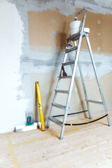 A stepladder with painting tools in a room. Preparing for putty
