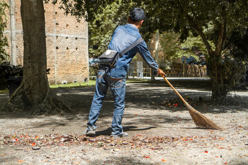 Man sweeps broom leaves in the garden in fall. on ground