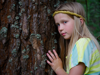 portrait of a blonde girl with blue eyes in green thickets