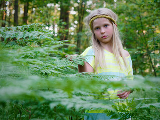 Naklejka premium portrait of a blonde girl with blue eyes in green thickets