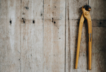 Close up of yellow nail puller pliers hanging on old wooden walls, copy space