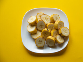 ripe bananas on a plate on a yellow background