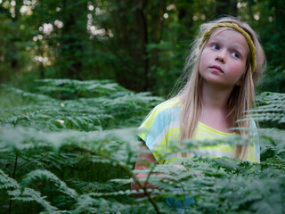portrait of a blonde girl with blue eyes in green thickets