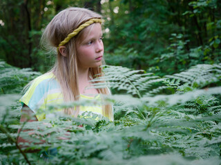 portrait of a blonde girl with blue eyes in green thickets