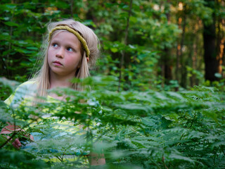 Naklejka premium portrait of a blonde girl with blue eyes in green thickets