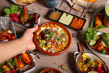 The waitress places the samosa chana chaat plate on the table. Culinary feast. Indian cuisine....