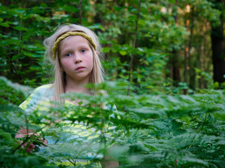 portrait of a blonde girl with blue eyes in green thickets
