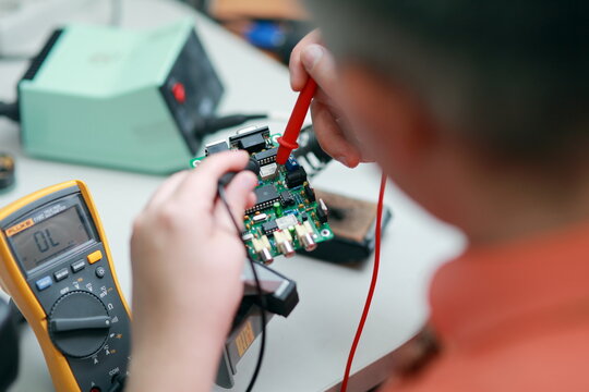 Hands of a man are engaged in the repair of electronics. Services, Manual assembly of the soldering circuit board.