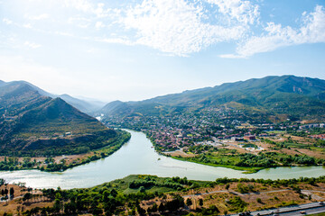 Panoramic top view of a mountain valley. River on a sunny day. Nature landscape. The confluence of the Aragvi and Kura rivers. Georgia, the city of Mtskheta © Inna Tolstorebrova