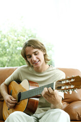 Teenage boy sitting on the couch playing guitar