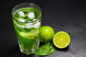 Mojito, lime and mint on a dark background. A refreshing cocktail in close-up.