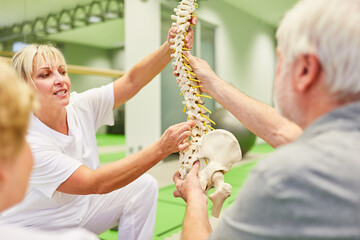 Senior and physiotherapist with spine model