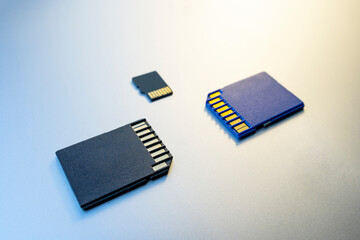 three SD Cards or memory cards for digital cameras and devices and on a gray metal surface.