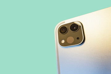 camera with lidar scanner and wide angle camera on the modern silver tablet, green surface in...